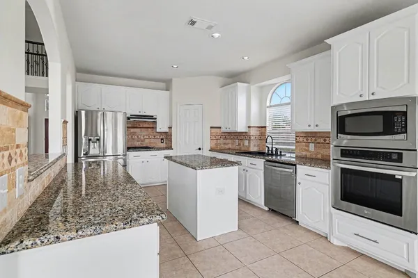 a kitchen with stainless steel appliances granite countertop a stove a sink and a microwave