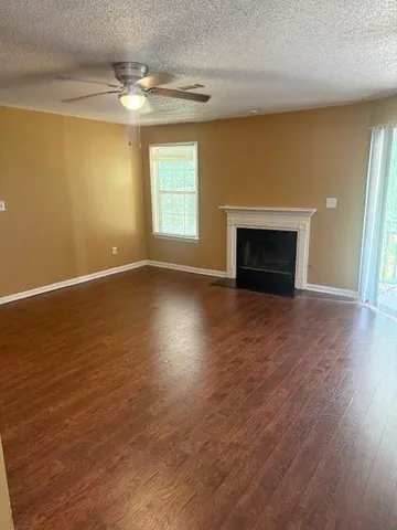 an empty room with wooden floor fireplace and windows