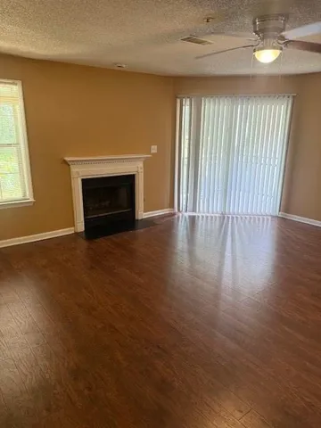 an empty room with wooden floor fireplace and windows