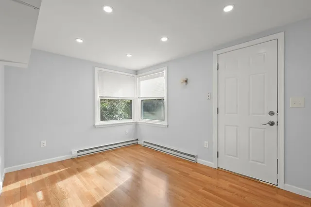 a view of an empty room with wooden floor and window