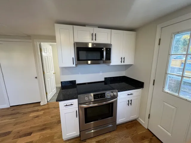 a kitchen with stainless steel appliances a stove a microwave and a hard wood floors