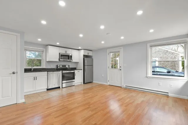 a kitchen with stainless steel appliances kitchen island granite countertop a stove a sink and a refrigerator with wooden floor