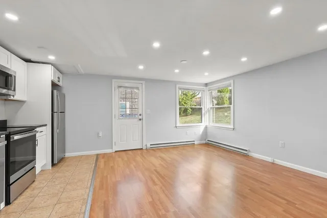 a view of an empty room with a window and wooden floor
