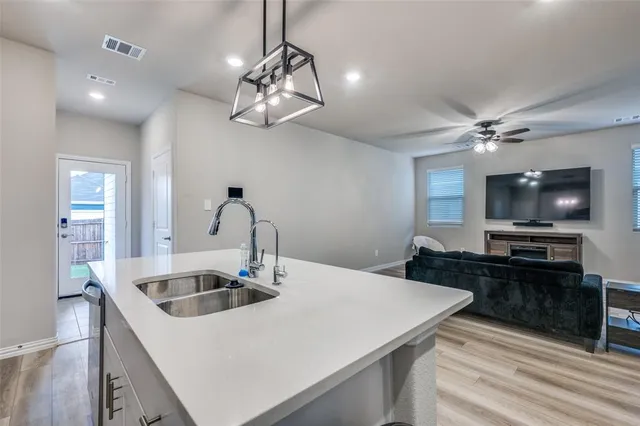 a kitchen with a sink a kitchen island with a stove and a refrigerator