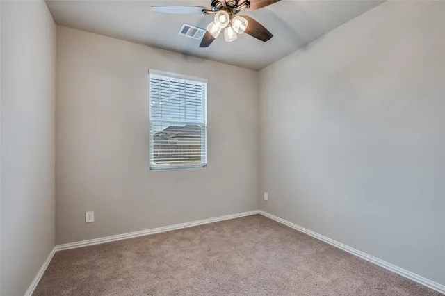 an empty room with a chandelier fan and windows