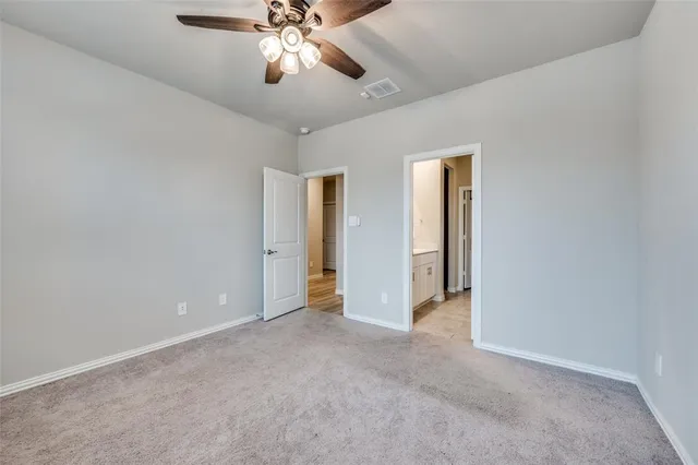 an empty room with a chandelier fan and closet area