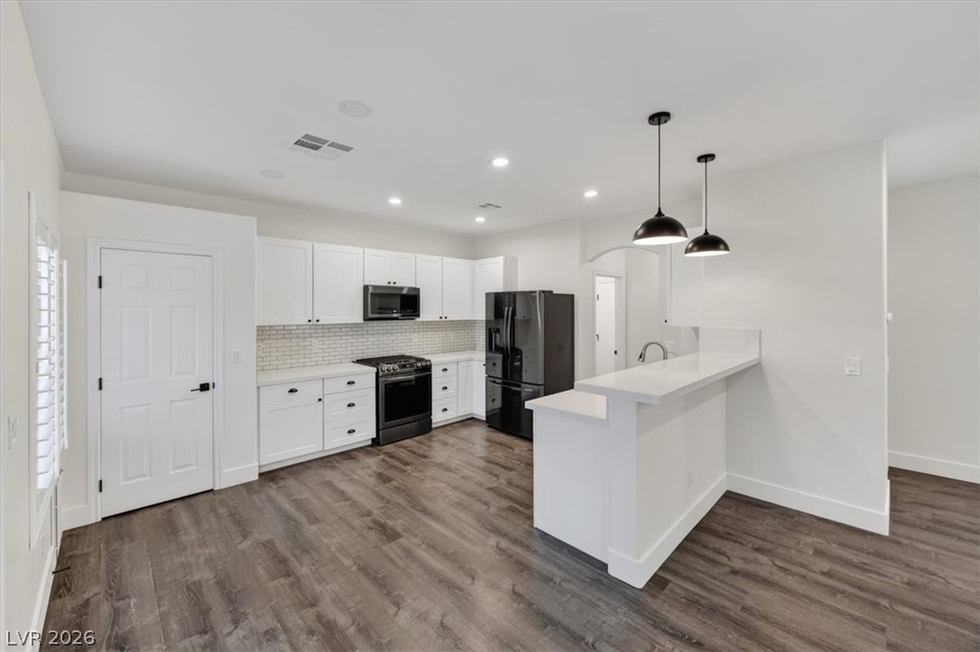 251 Integrity Ridge Drive Henderson, NV 89052 - Photo 3 of 32 Gleaming stone counters and rich wood-toned flooring anchor this contemporary kitchen space.