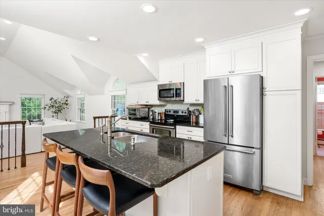 a kitchen with stainless steel appliances granite countertop a refrigerator a stove a sink a dining table and chairs