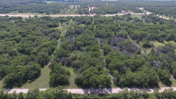 an aerial view of residential houses with outdoor space and trees
