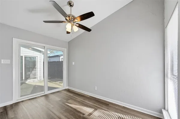 an empty room with wooden floor fan and windows