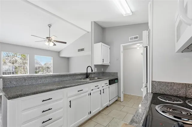 a kitchen with granite countertop white cabinets and stainless steel appliances