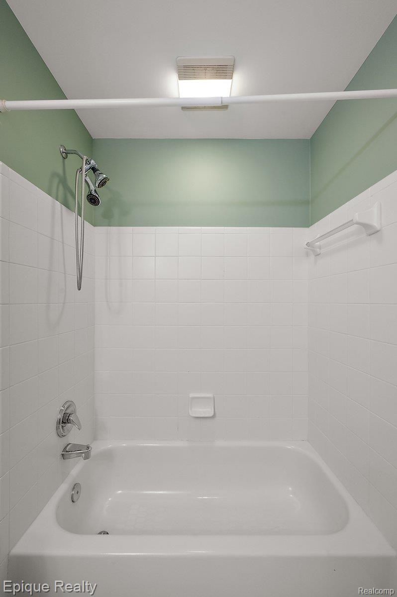 1909 Catlin Drive Rochester, MI 48306 - Photo 37 of 76 Bathtub and shower combination featuring white subway tile surround, chrome fixtures, and a green painted upper wall