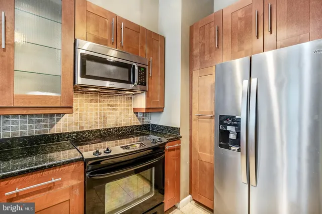 a kitchen with stainless steel appliances granite countertop a stove a refrigerator and a stove top oven