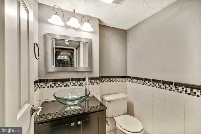 a bathroom with a granite countertop sink a toilet and a mirror
