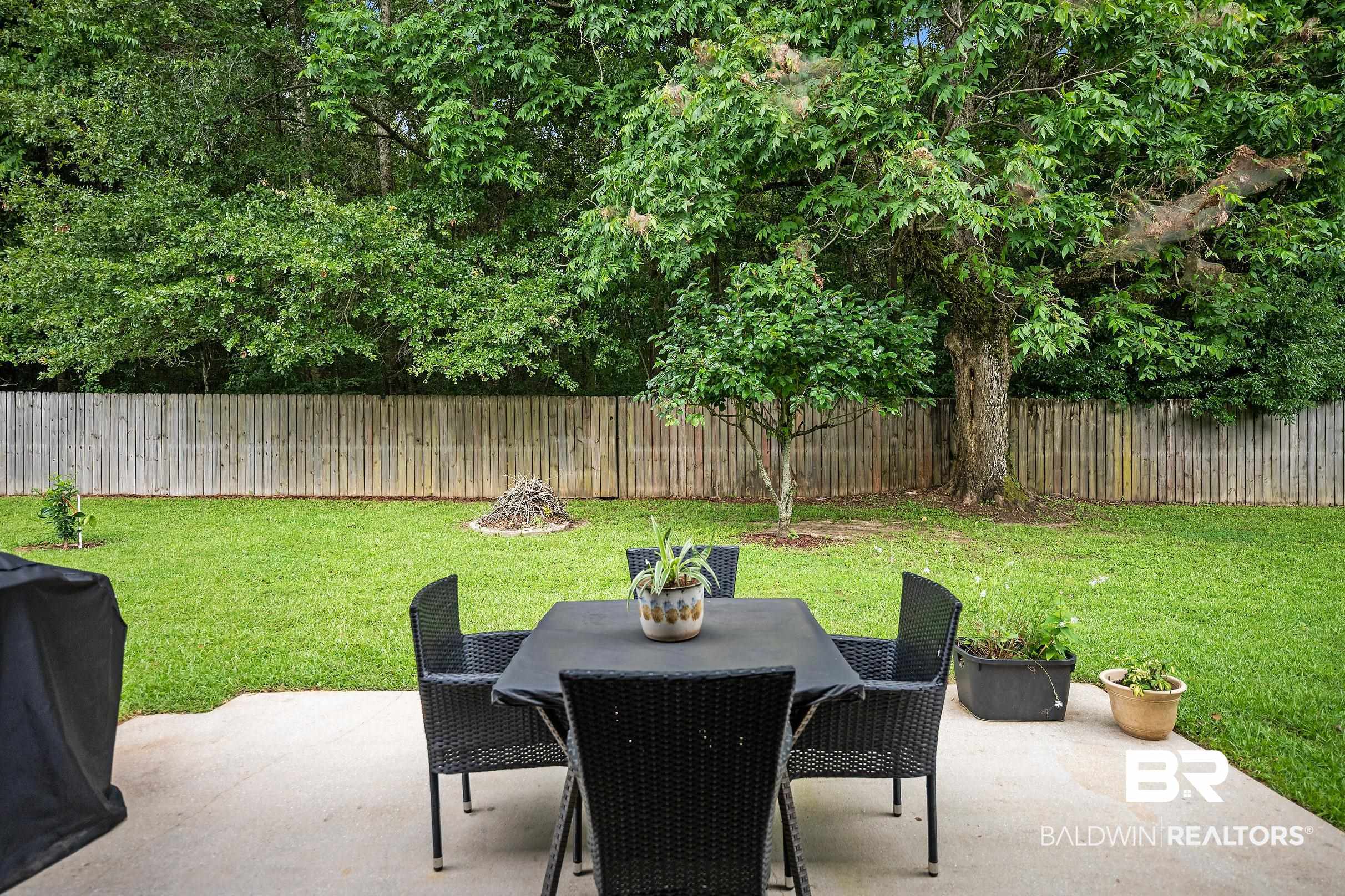313 Pecan Ridge Boulevard Fairhope, AL 36532 - Photo 32 of 51 Expansive backyard featuring a large concrete patio, mature trees, a manicured lawn, and a wood privacy fence