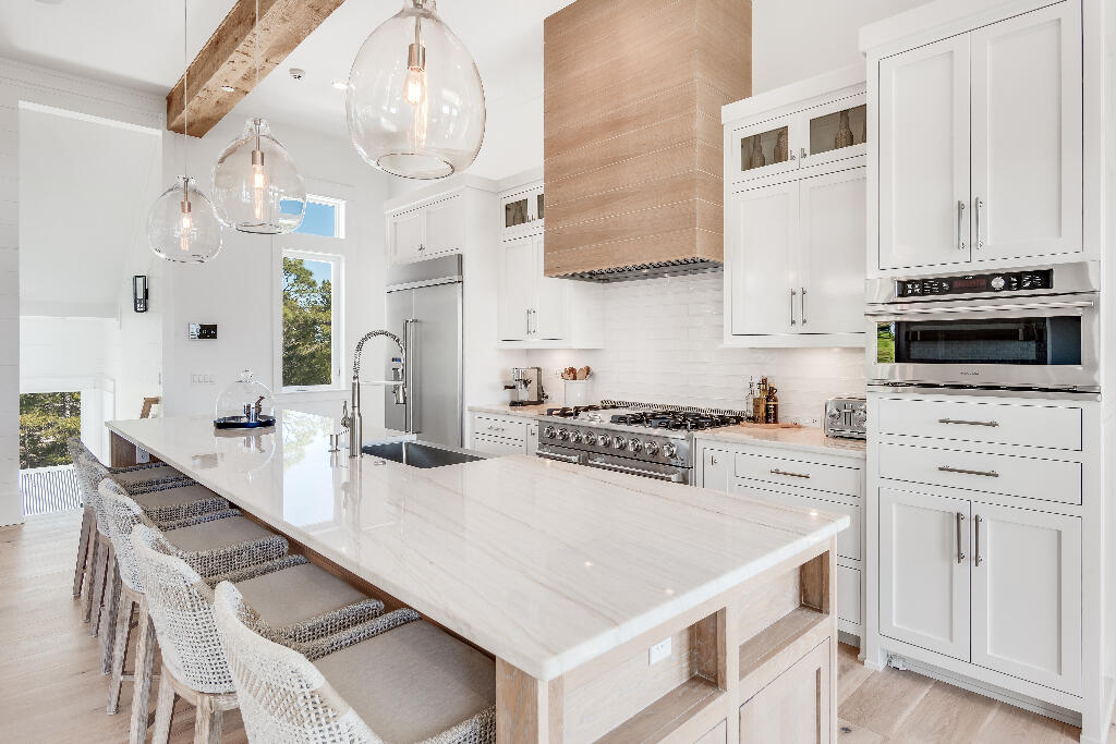 90 Sandstone Street Santa Rosa Beach, FL 32459 - Photo 51 of 73 a kitchen with stainless steel appliances kitchen island granite countertop a table chairs in it and white cabinets
