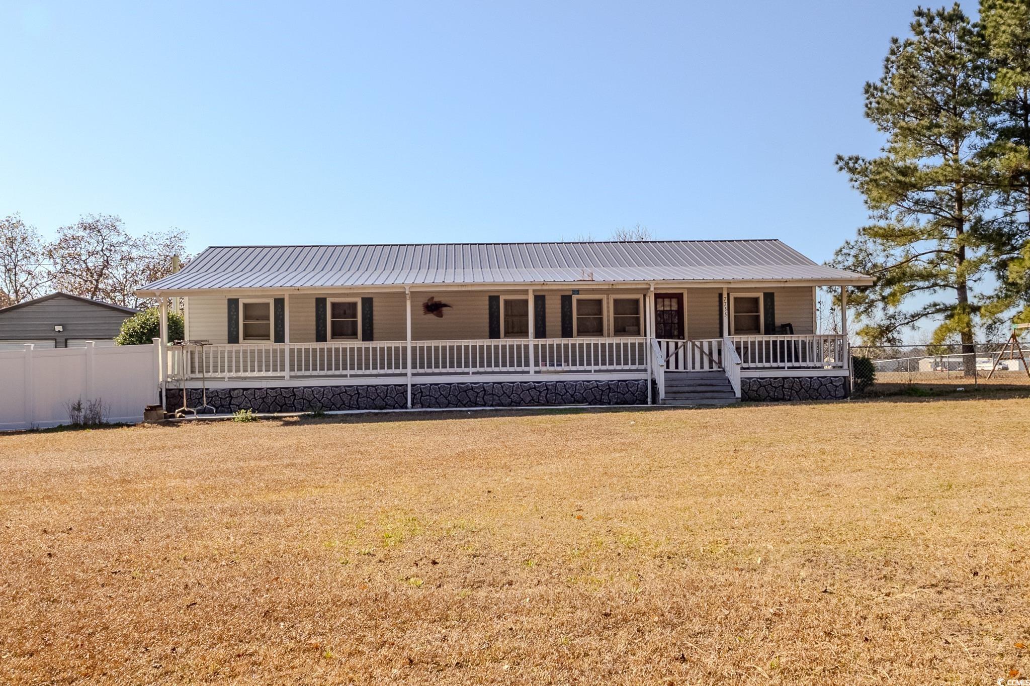 Farmhouse-style home featuring a porch and a metal roof