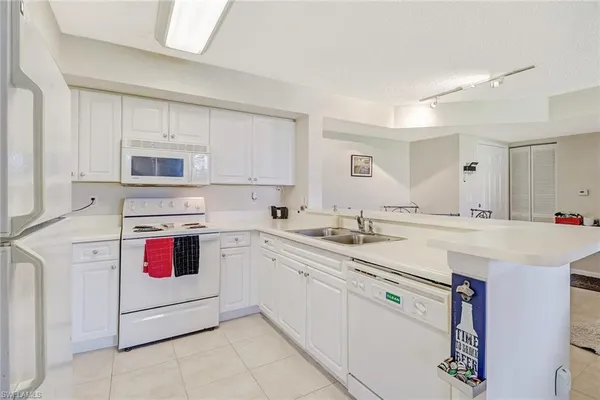 a kitchen with granite countertop cabinets sink and white appliances