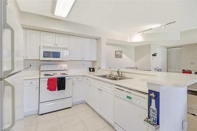 a kitchen with granite countertop cabinets sink and white appliances