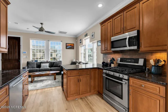 a kitchen with granite countertop a stove top oven a sink dishwasher and cabinets with wooden floor
