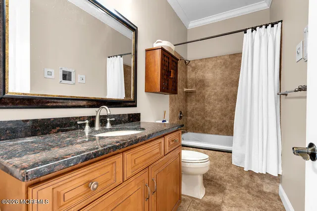a bathroom with a granite countertop sink a toilet a mirror a vanity and shower