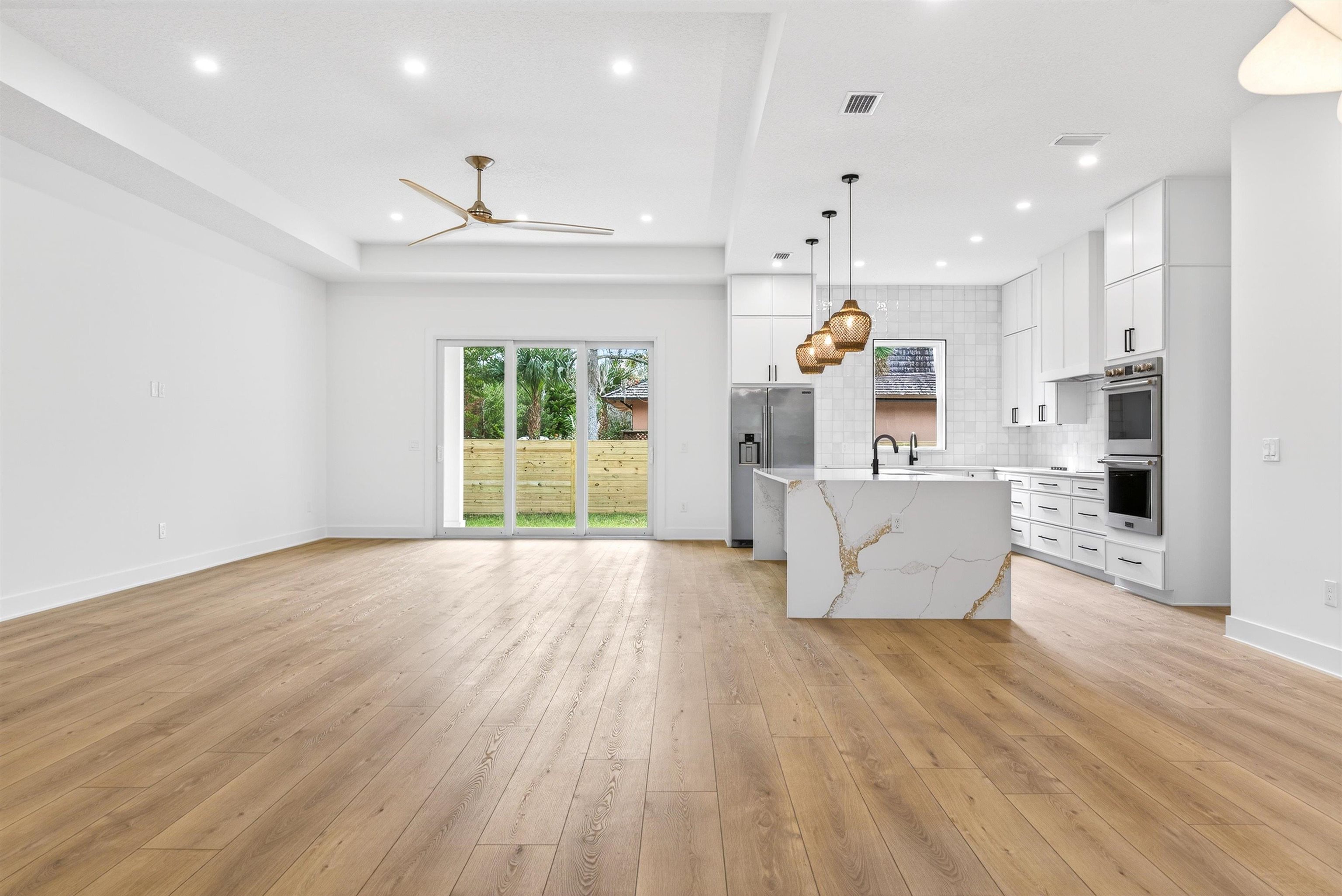 16 Baru Road St. Augustine, FL 32080 - Photo 71 of 73 Kitchen featuring open floor plan, white cabinetry, hanging light fixtures, a center island with sink, and light wood-type flooring