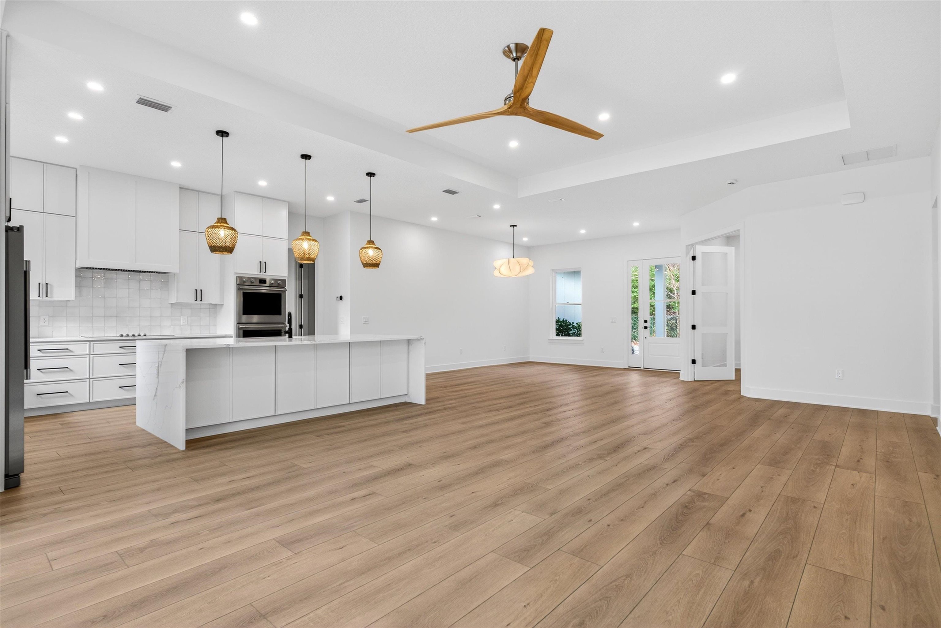 16 Baru Road St. Augustine, FL 32080 - Photo 18 of 73 Unfurnished living room with light wood-style flooring, a ceiling fan, a tray ceiling, and recessed lighting