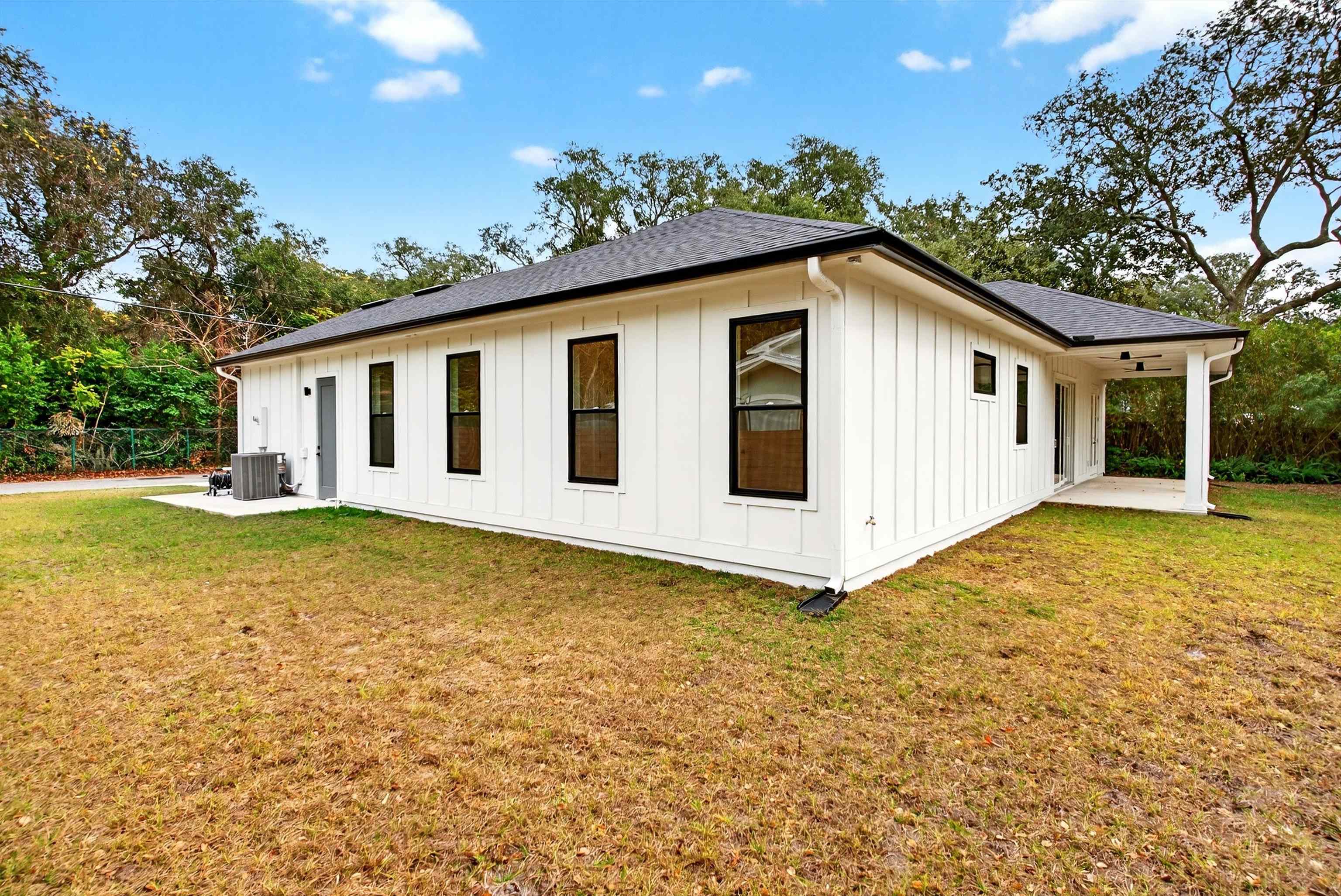 16 Baru Road St. Augustine, FL 32080 - Photo 56 of 73 View of property exterior featuring board and batten siding, a lawn, a patio, and a shingled roof