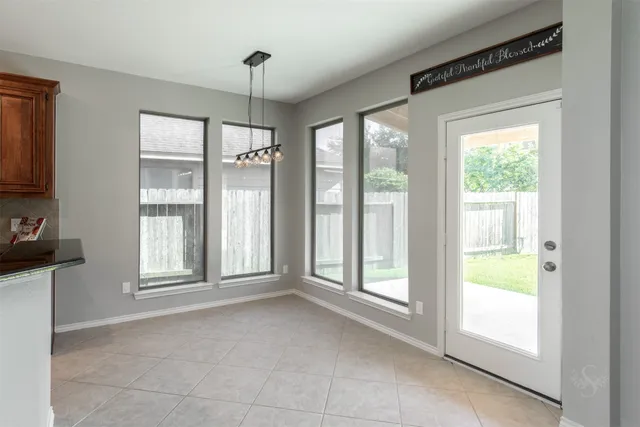 a view of an empty room with a window and chandelier fan