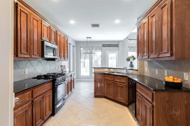 a kitchen with stainless steel appliances granite countertop wooden cabinets a sink and dishwasher a stove top oven with wooden floor