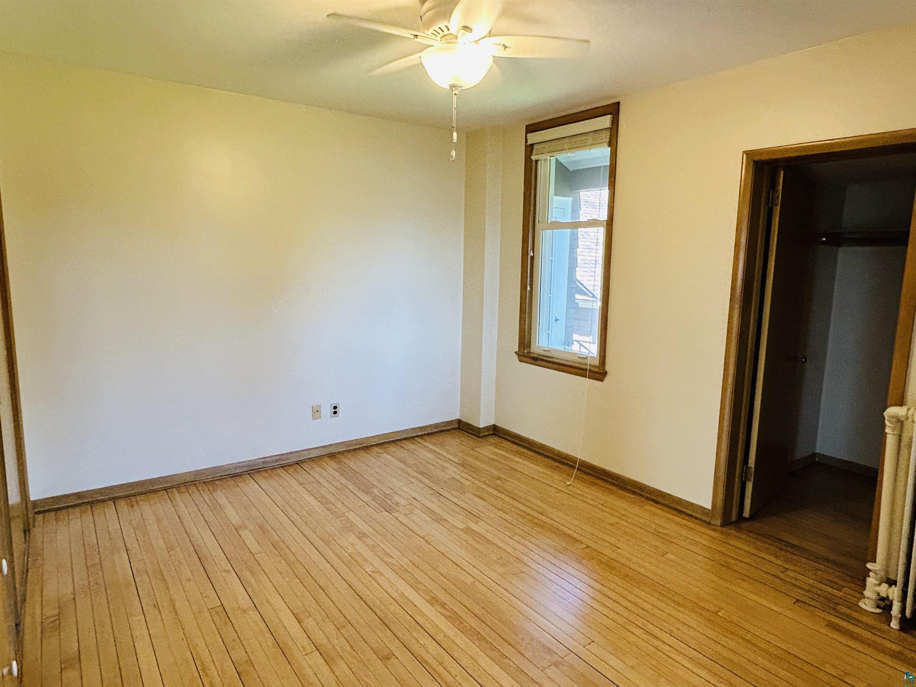 5090 London Road, Unit 1 Duluth, MN 55804 - Photo 28 of 54 Room featuring wood-finish flooring, a ceiling fan with integrated lighting, and a single window with wood trim