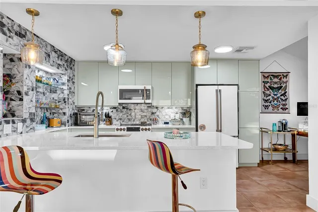 a kitchen with stainless steel appliances kitchen island granite countertop a sink dishwasher a dining table and chairs with wooden floor