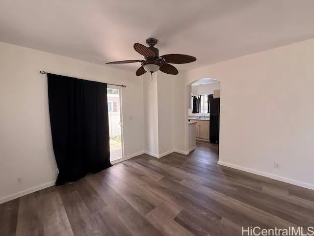a view of an empty room with wooden floor and a ceiling fan