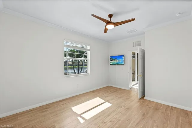 an empty room with windows and ceiling fan
