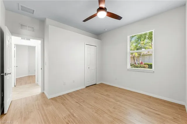 a view of empty room with wooden floor and fan