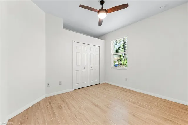 an empty room with ceiling fan and windows