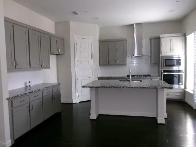 a kitchen with kitchen island granite countertop a sink cabinets and stainless steel appliances