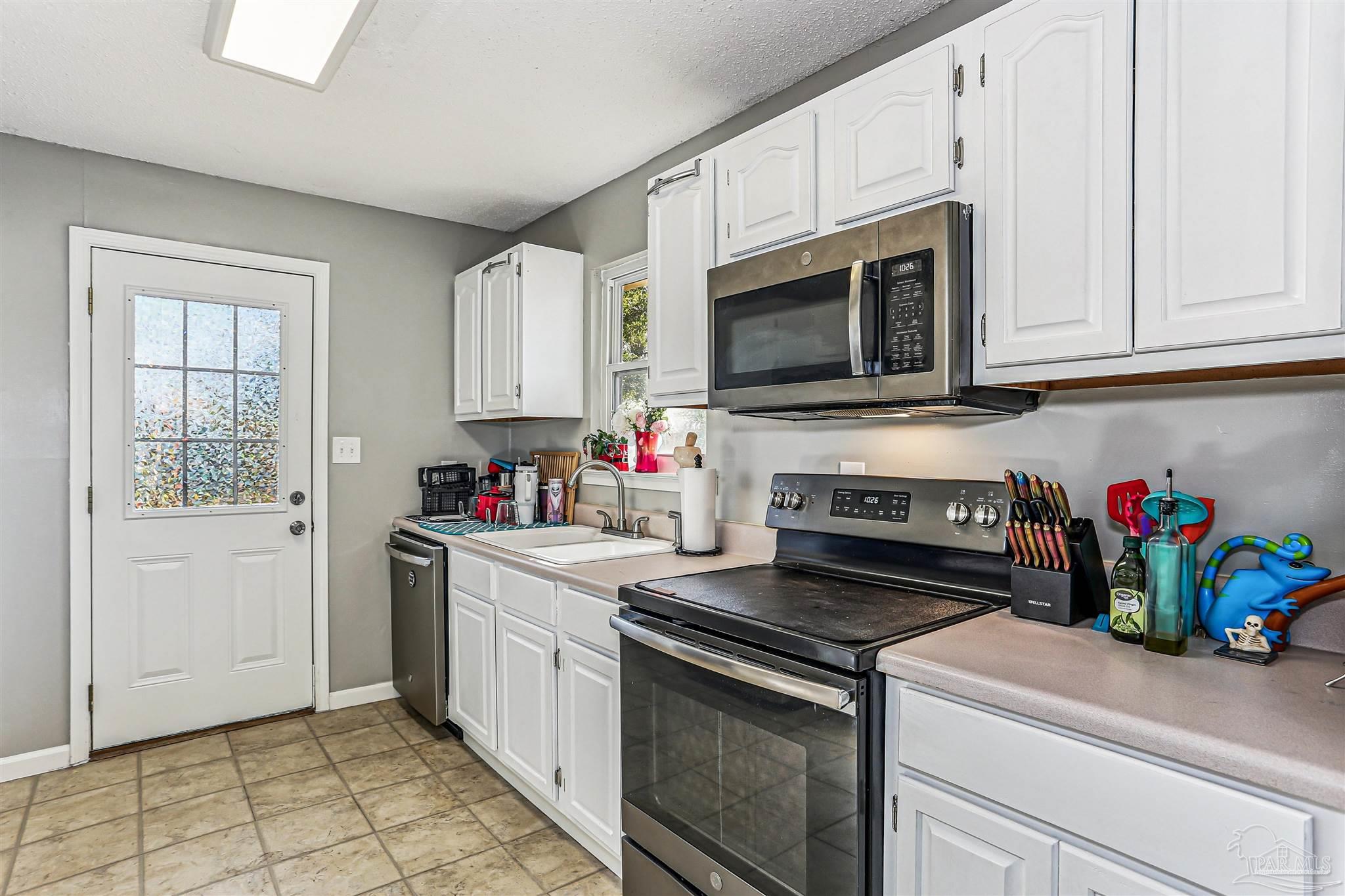 6810 Myra Road Molino, FL 32577 - Photo 14 of 20 a kitchen with stainless steel appliances white cabinets and a stove top oven
