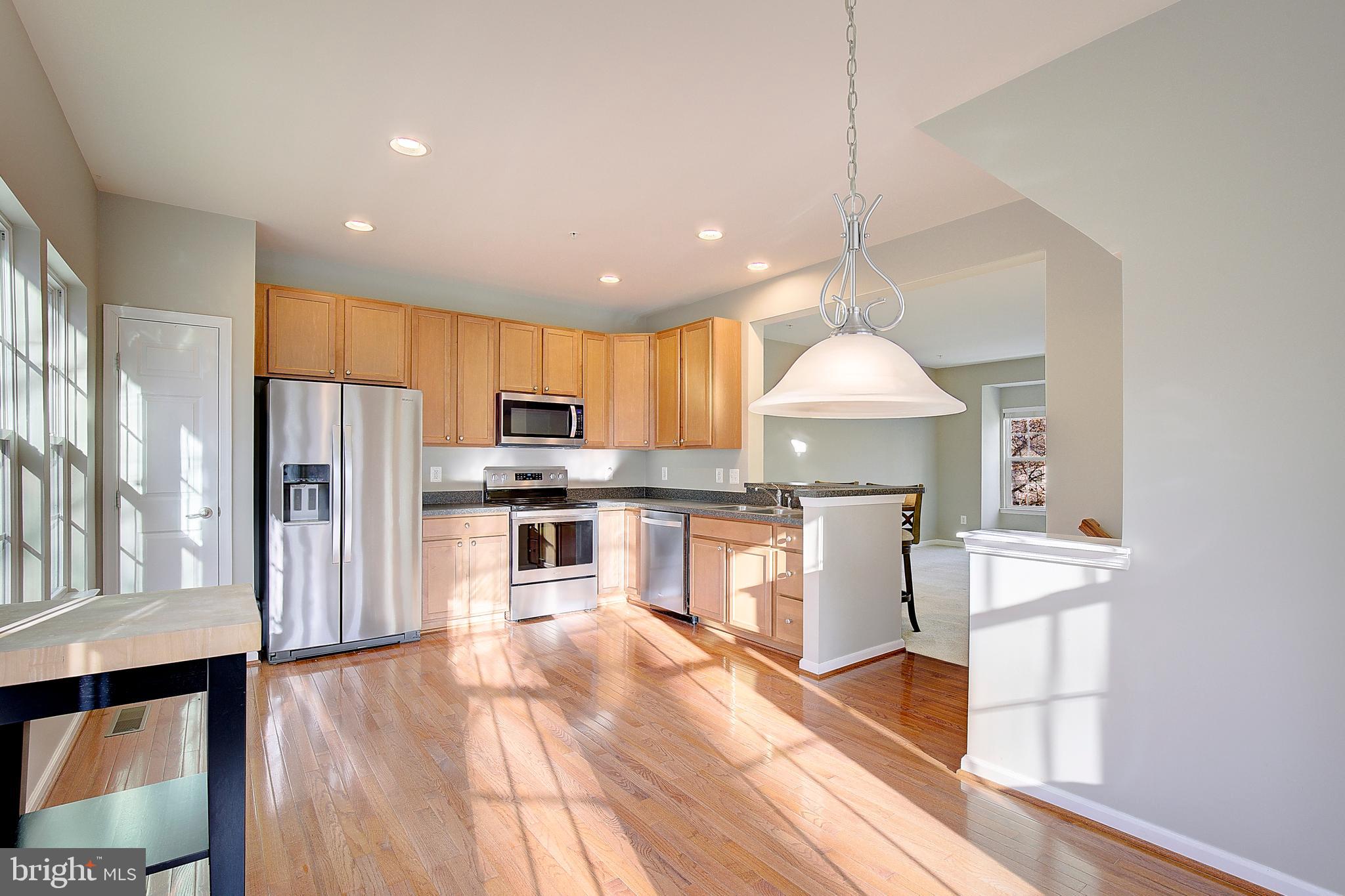 8410 Clear Spring Drive, Unit 1 Chesapeake Beach, MD 20732 - Photo 28 of 41 a kitchen with stainless steel appliances granite countertop a refrigerator a sink dishwasher a stove and a dining table with wooden floor