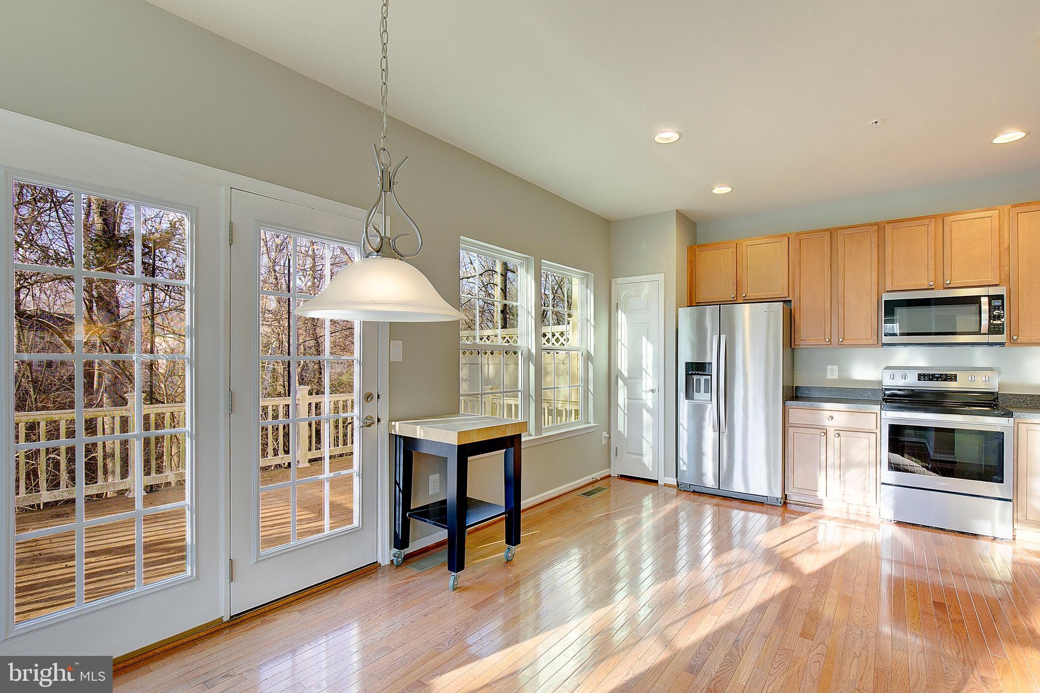 8410 Clear Spring Drive, Unit 1 Chesapeake Beach, MD 20732 - Photo 29 of 41 a view of kitchen with stainless steel appliances granite countertop a stove a refrigerator a microwave oven with cabinets and wooden floor