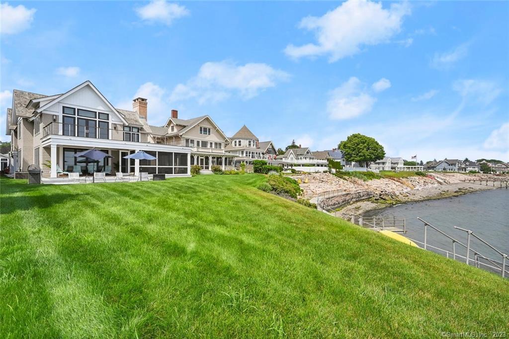 a front view of a house with a garden and lake view
