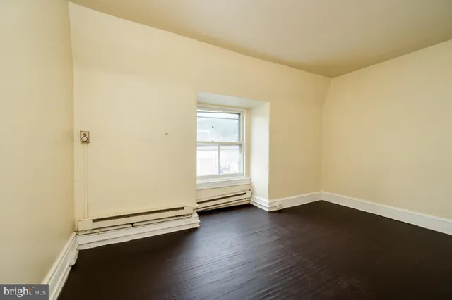 an empty room with wooden floor and white walls