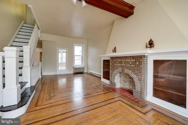 a view of an empty room with wooden floor and a fireplace