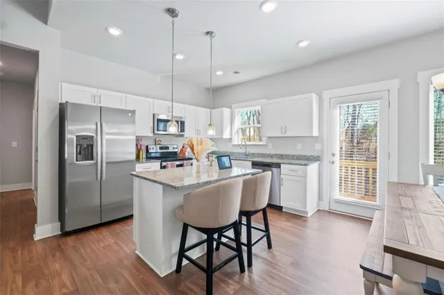 a kitchen with stainless steel appliances granite countertop a table chairs refrigerator and microwave