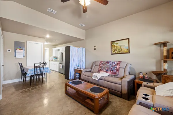 a living room with furniture a chandelier fan and a dining table
