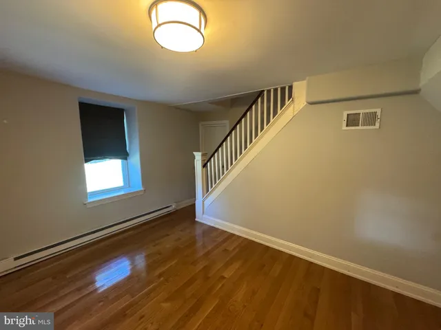 a view of an empty room with wooden floor and windows