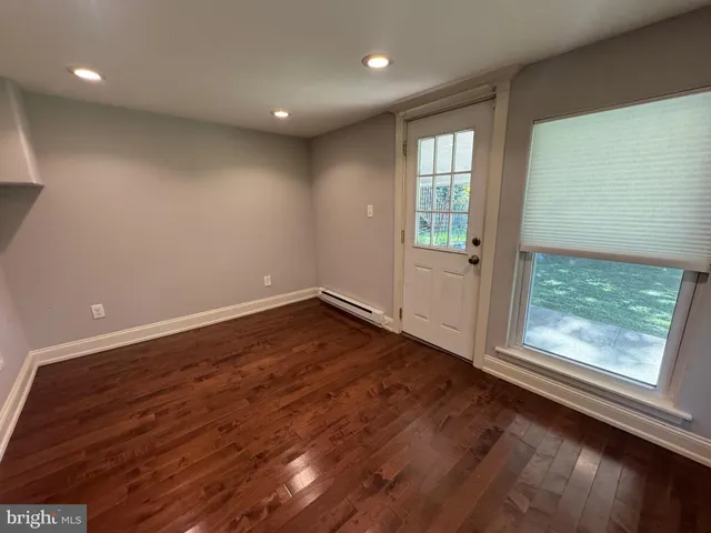 an empty room with wooden floor and windows