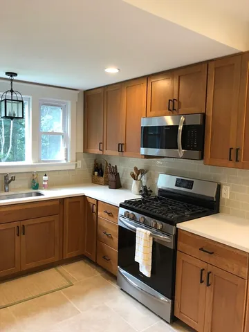 a kitchen with stainless steel appliances granite countertop wooden cabinets a stove top oven a sink and dishwasher