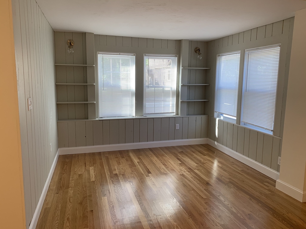 140 Ames Street, Unit 1 Sharon, MA 02067 - Photo 9 of 16 an empty room with wooden floor and windows