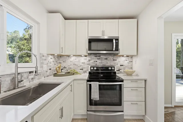 a kitchen with cabinets stainless steel appliances a sink and a window